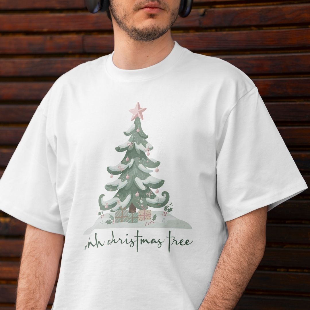 Close-up of a person wearing a white t-shirt featuring a colorful "ohh christmas tree" lettering and holiday snow-covered tree design.