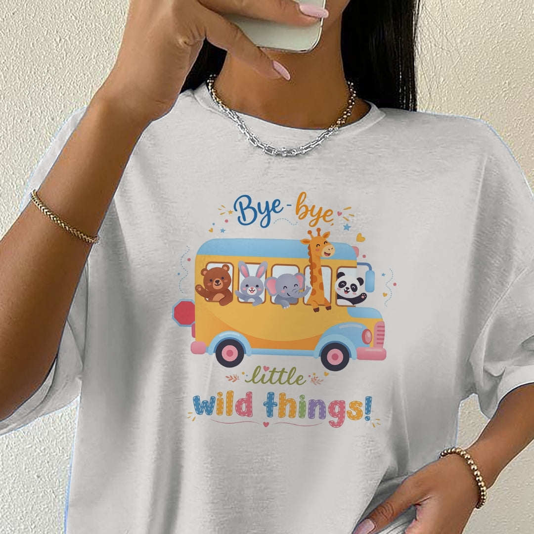 Person wearing a white t-shirt with a colorful graphic of animals on a bus and text.