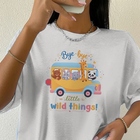 Person wearing a white t-shirt with a colorful graphic of animals on a bus and text.