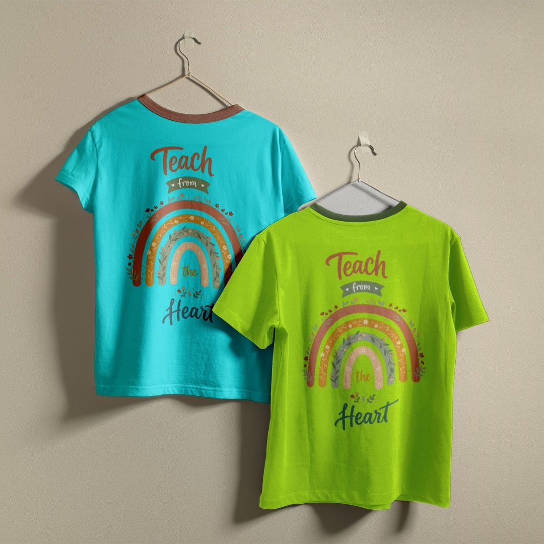 Two children's short-sleeve t-shirts hanging on hangers against a plain beige wall. One shirt is turquoise blue and the other is bright lime green, both featuring a colorful rainbow graphic and the words 'Teach from the Heart' on the back.