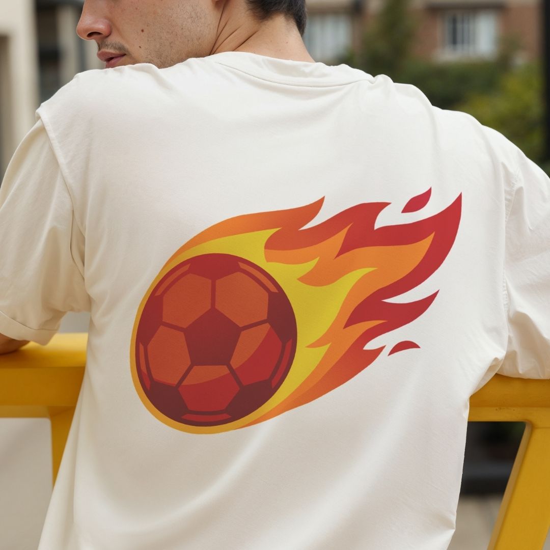Rear view of a man wearing an off-white cream t-shirt showcasing a large back print of a stylized red soccer ball surrounded by bold trailing flames.