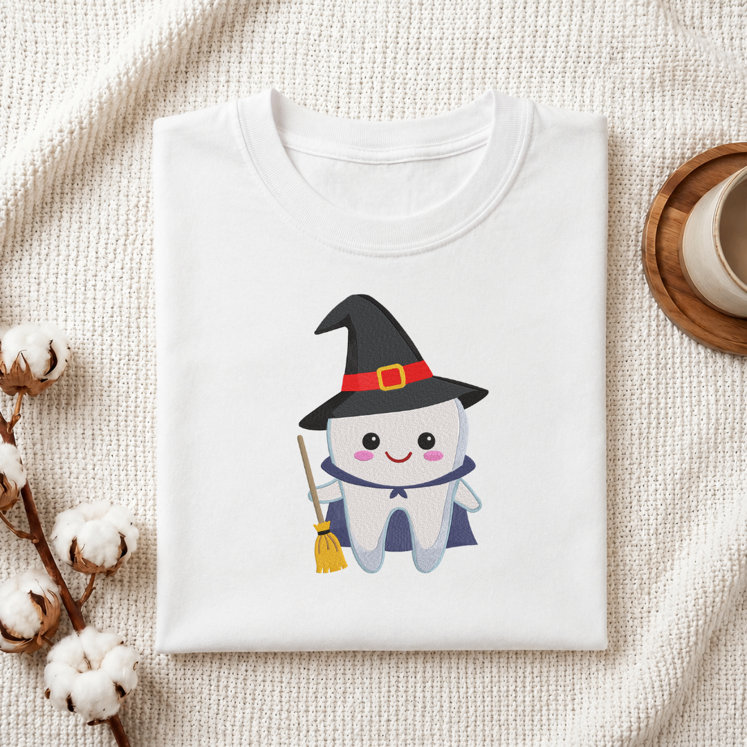 Folded white cotton t-shirt mockup featuring a cute witch tooth machine embroidery design, styled with cotton stems and a wooden cup