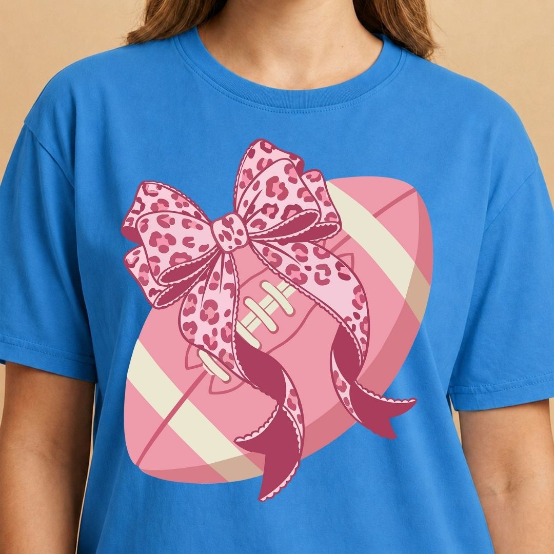 Blue t-shirt with a pink football and leopard print bow design on a beige background