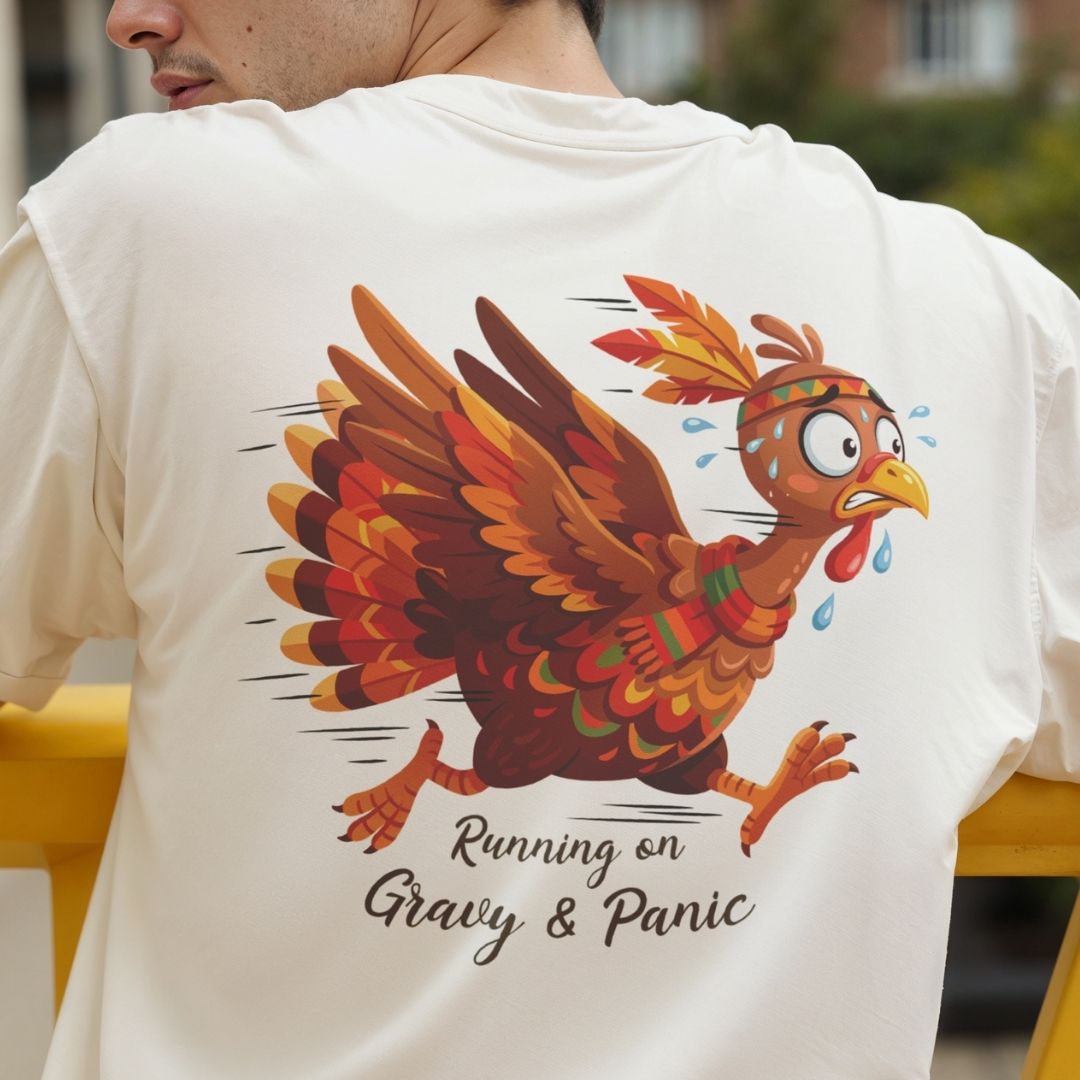 A person wearing a white T-shirt, shown from the back, featuring a colorful cartoon turkey graphic with the text 'Running on Gravy & Panic'.