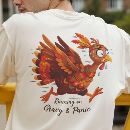 A person wearing a white T-shirt, shown from the back, featuring a colorful cartoon turkey graphic with the text 'Running on Gravy & Panic'.