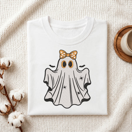 Folded white t-shirt featuring an embroidered ghost with an orange bow and tiny spiders.