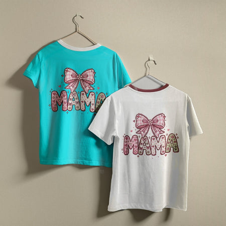 Two t-shirts hanging on a wall, one bright turquoise blue and one white, both printed with a whimsical pink gingham "MAMA" bow graphic.