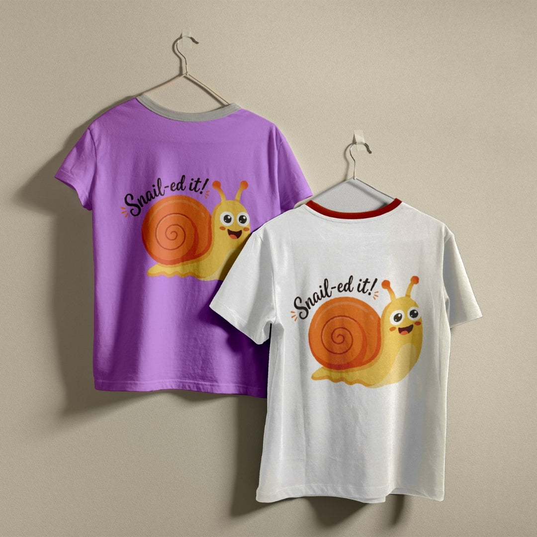 Two t-shirts hanging on hangers, one purple and one white, both printed with a smiling cartoon snail graphic and the text "Snail-ed it!".