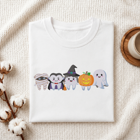 Folded white cotton t-shirt mockup featuring a cute Halloween dental teeth characters machine embroidery design, styled with cotton stems and a wooden cup