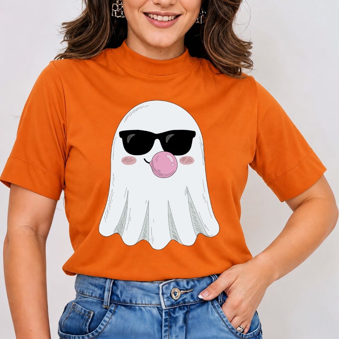 A woman wearing a bright orange short-sleeve mock-neck t-shirt with a cartoon ghost graphic wearing black sunglasses and blowing a pink bubblegum bubble. She is also wearing blue jeans.