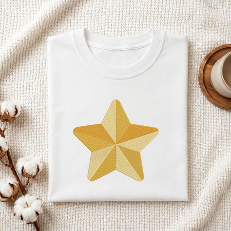 Folded white cotton t-shirt mockup featuring a segmented golden star machine embroidery design, styled with cotton stems and a wooden cup