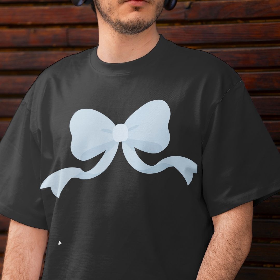 A man wearing a black t-shirt with a large, light blue bow graphic printed on the chest, set against a dark wooden plank background.