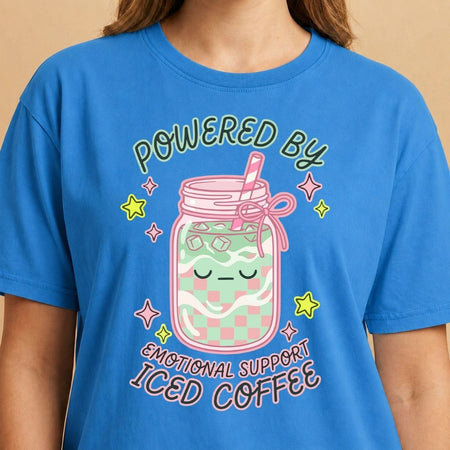 Blue t-shirt with a design of a mason jar with ice coffee and text 'Powered by Emotional Support Iced Coffee' on a beige background.