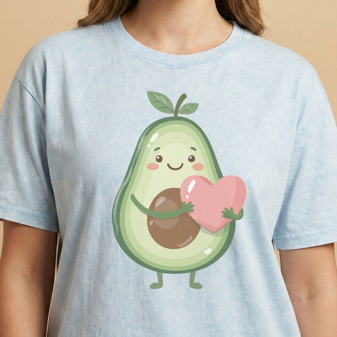 Light blue t-shirt with a cartoon avocado holding a heart on a beige background