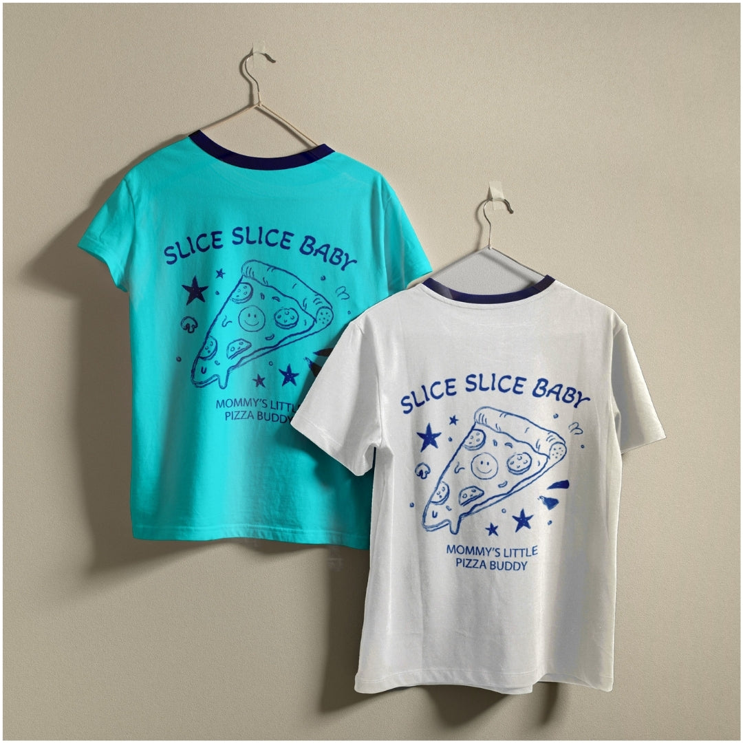 Two t-shirts hanging on a wall, one bright teal blue and one white, both featuring the retro line art "Slice Slice Baby" pizza slice design.