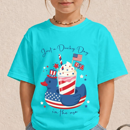 A young child wearing a bright cyan turquoise t-shirt displaying a colorful "Sippin' on Freedom" frozen drink graphic on the front.