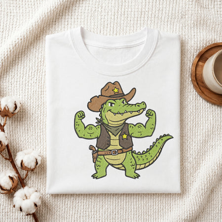 Folded white t-shirt mockup with a detailed cowboy alligator embroidery design on the chest.