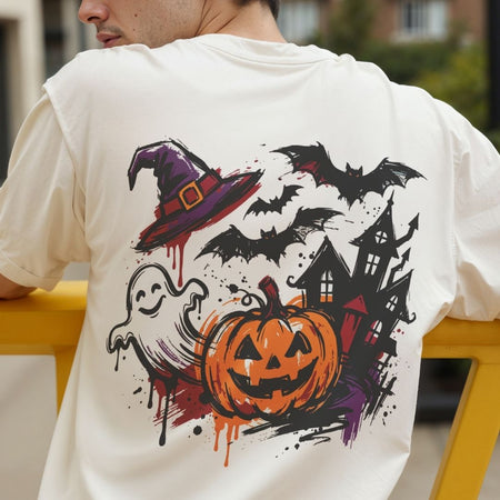 A person wearing a white T-shirt shown from the back, featuring a large Halloween graphic print with a witch hat, bats, ghost, haunted house, and jack-o'-lantern in orange, black, purple, and red.