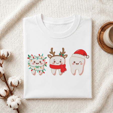 Folded white cotton t-shirt mockup featuring a cute Christmas teeth characters machine embroidery design, styled with cotton stems and a wooden cup