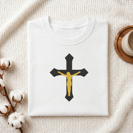 Folded white cotton t-shirt featuring a black and gold crucifix embroidery design centered on the chest.