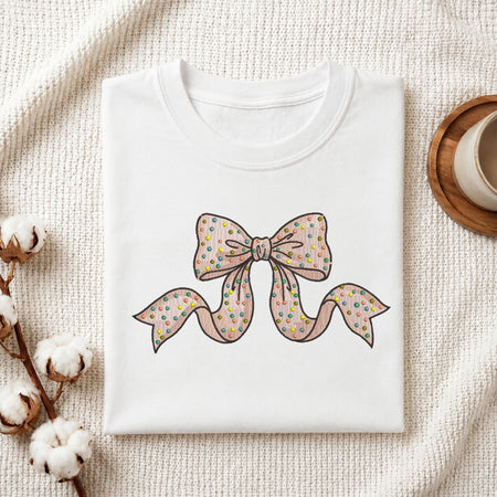 Polka dot bow embroidery stitched onto a folded white t-shirt.