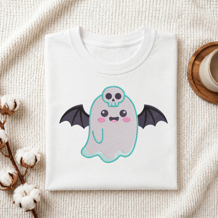A folded white t-shirt with a cute cartoon ghost graphic, styled on a textured cream fabric with cotton bolls and a coffee cup in the background.