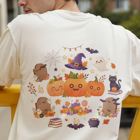 A person wearing a white T-shirt shown from the back, featuring a colorful Halloween-themed graphic print with pumpkins, a witch hat, ghosts, bats, tombstones, and autumn leaves.