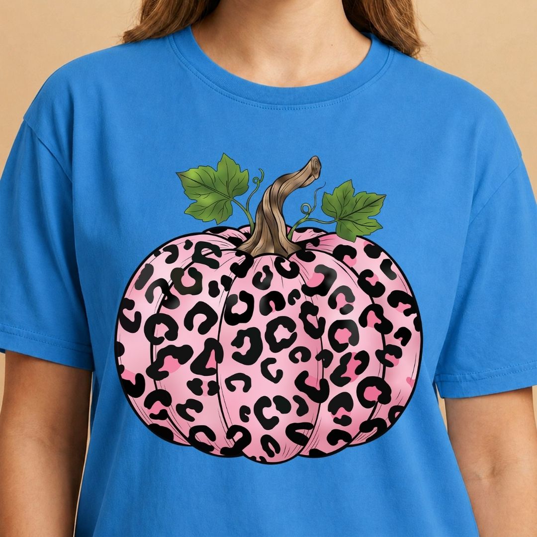 Blue t-shirt with a pink leopard print pumpkin design on a beige background
