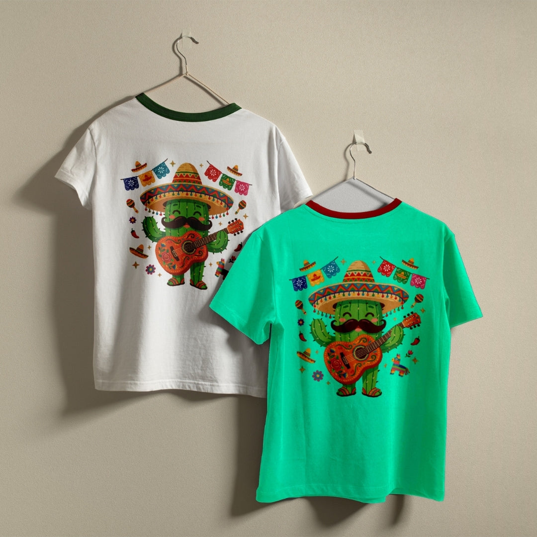 Two children's ringer t-shirts displayed on hangers against a plain beige wall. The left shirt is white with a dark green collar and features a colorful graphic of a green cactus character wearing a sombrero and playing a guitar.