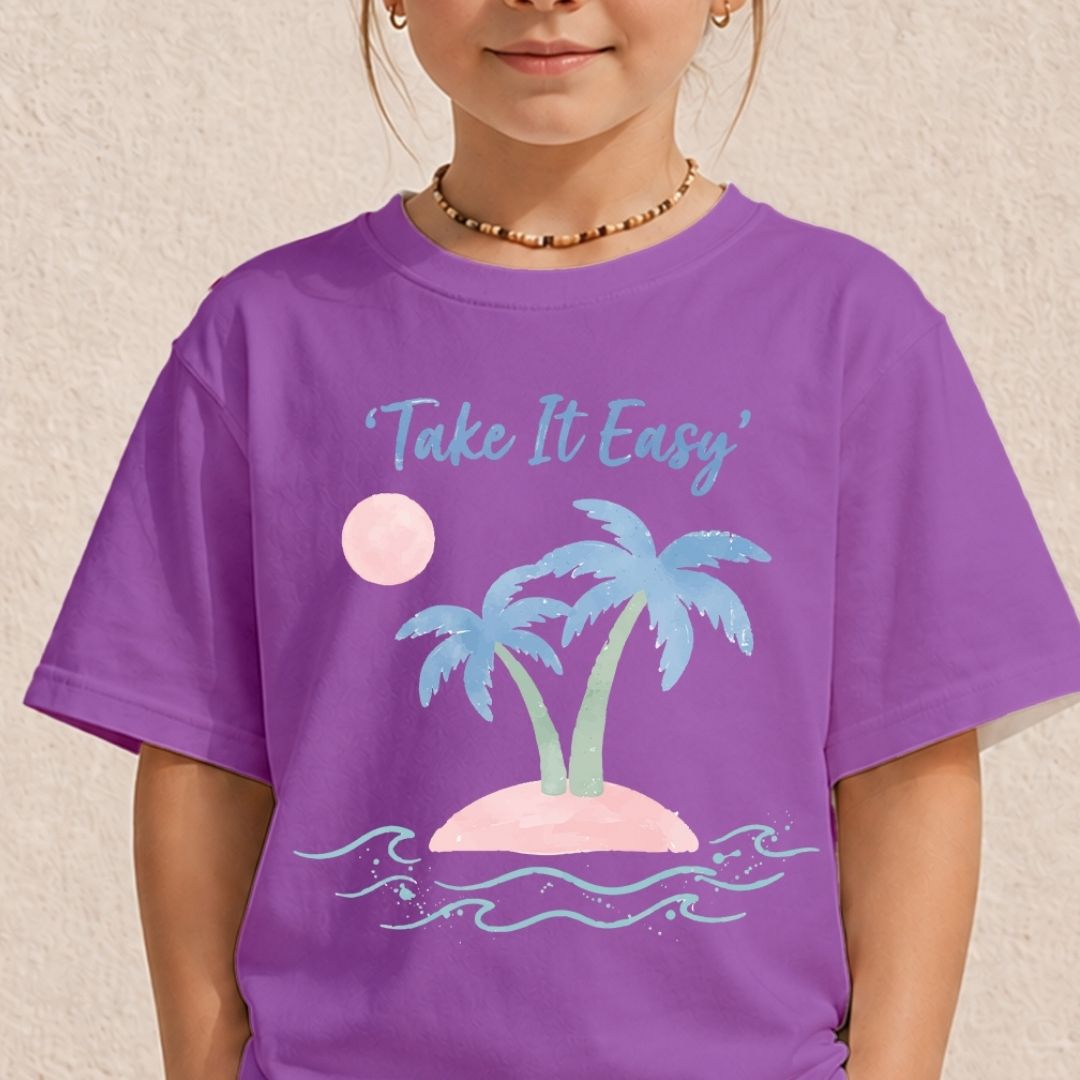 A child wearing a purple short-sleeve t-shirt with a graphic of a tropical island, palm trees, a pink sun, and the text 'Take It Easy' in light blue. The child is shown from the chin down against a textured beige wall.