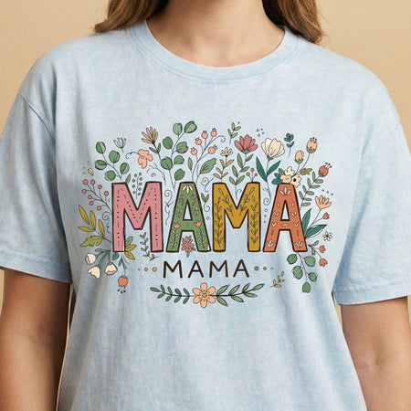 Light blue t-shirt with 'MAMA' text surrounded by floral designs on a beige background