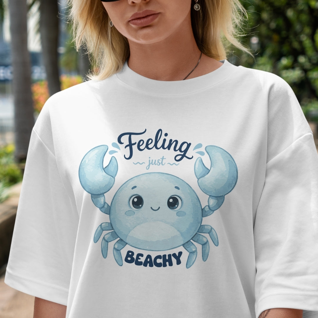 Person wearing a white t-shirt with a blue crab graphic and text outdoors.