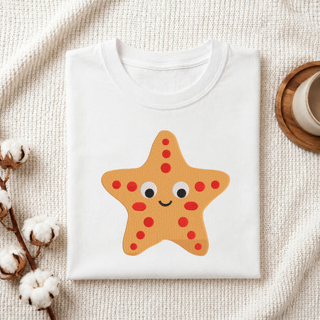 Folded white cotton t-shirt featuring an embroidered cute smiling starfish design, placed on a white knitted background.