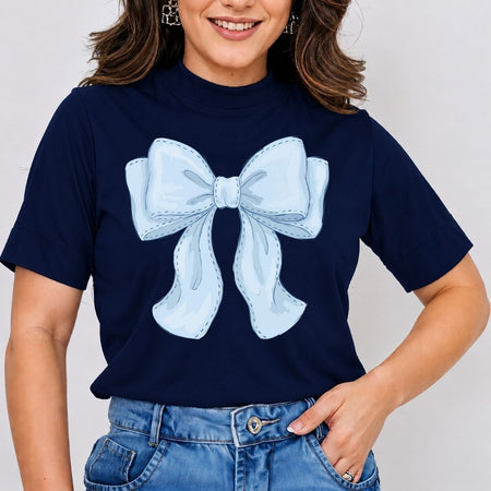A woman wearing a navy blue short-sleeve t-shirt with a large light blue bow graphic on the front, paired with blue jeans.