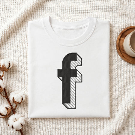 A neatly folded white crewneck t-shirt featuring a stitched 3D block lowercase letter "f" design, styled with cotton branches and a wooden coaster.