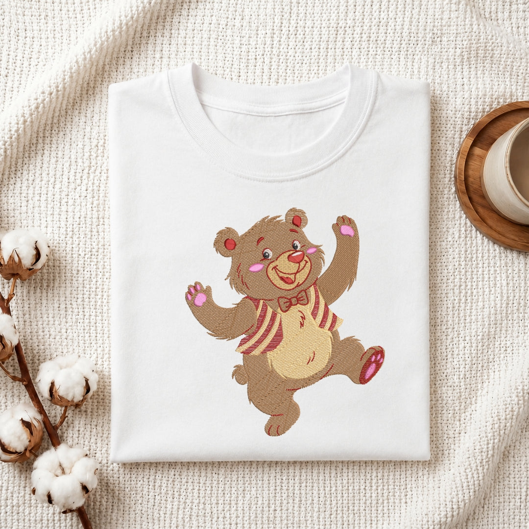 A white t-shirt featuring an embroidered dancing bear wearing a striped vest and bow tie.