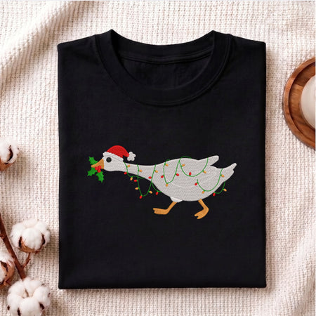 Folded black t-shirt featuring an embroidered goose wrapped in Christmas lights.