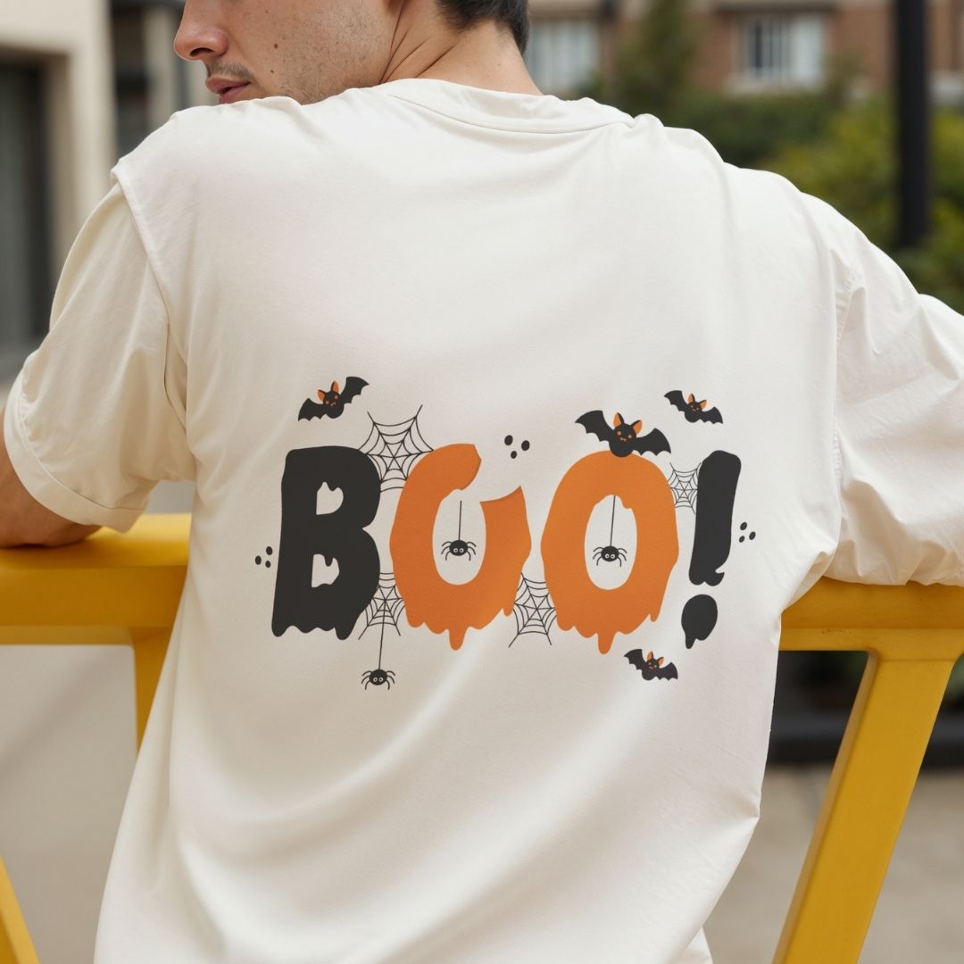 Back view of a person wearing an off-white t-shirt featuring a large Halloween "BOO!" graphic with hanging spiders and bats.

