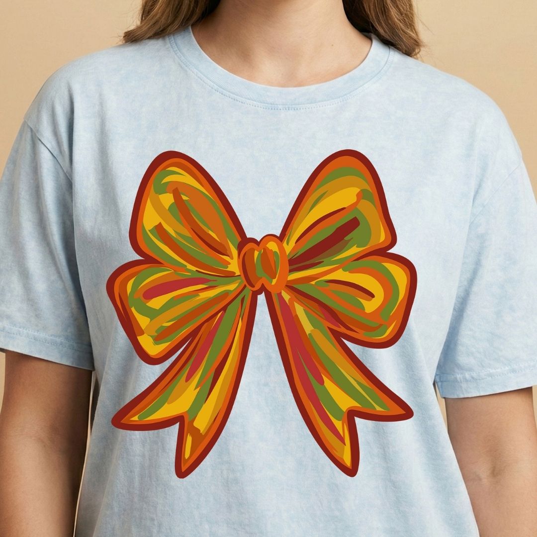 Light blue t-shirt with a large, colorful bow graphic on a beige background
