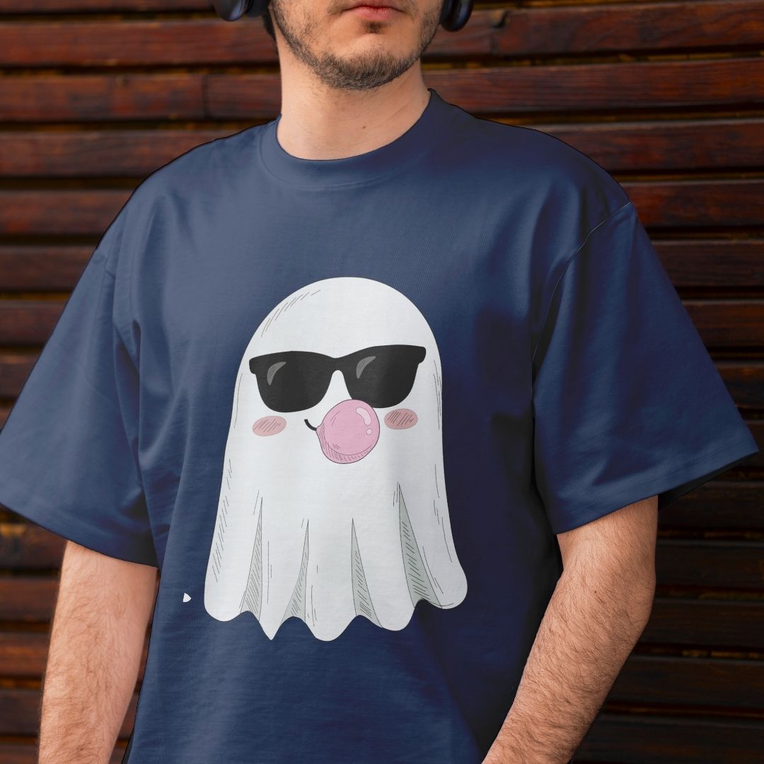 A man wearing a navy blue t-shirt with a cartoon ghost graphic wearing black sunglasses and blowing a pink bubblegum bubble, set against a dark wooden slat wall.