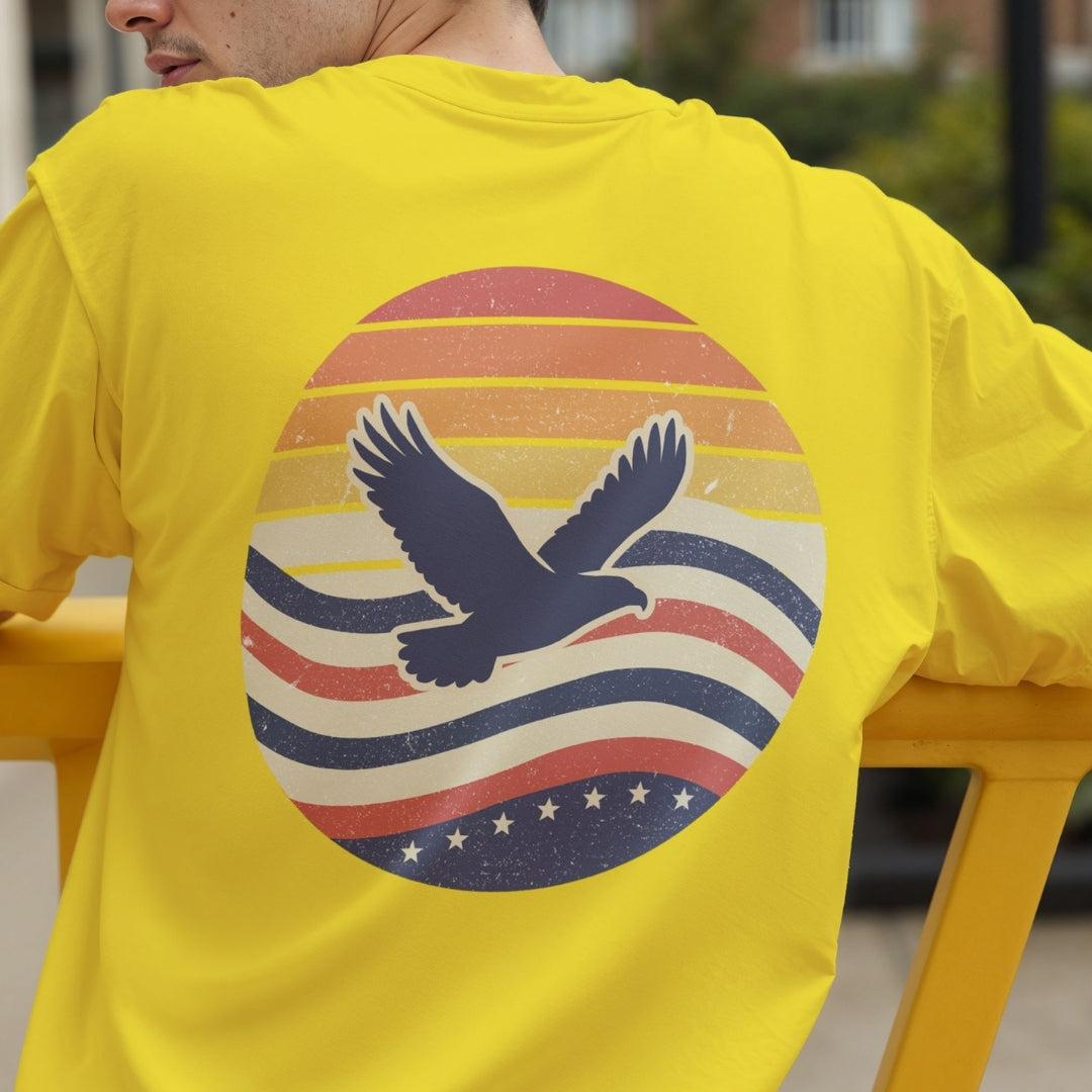Back view of a person wearing a bright yellow t-shirt showcasing the retro sunset and flying eagle graphic.