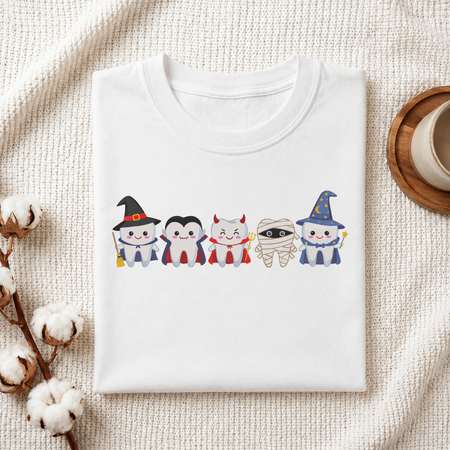Folded white cotton t-shirt mockup featuring a cute Halloween teeth characters machine embroidery design, styled with cotton stems and a wooden cup
