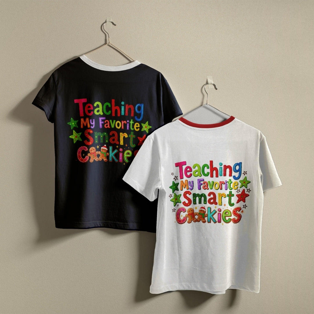 Two short-sleeve ringer T-shirts hanging on hangers against a plain beige wall. The left shirt is black with a colorful text graphic reading 'Teaching My Favorite Smart Cookies' on the back.