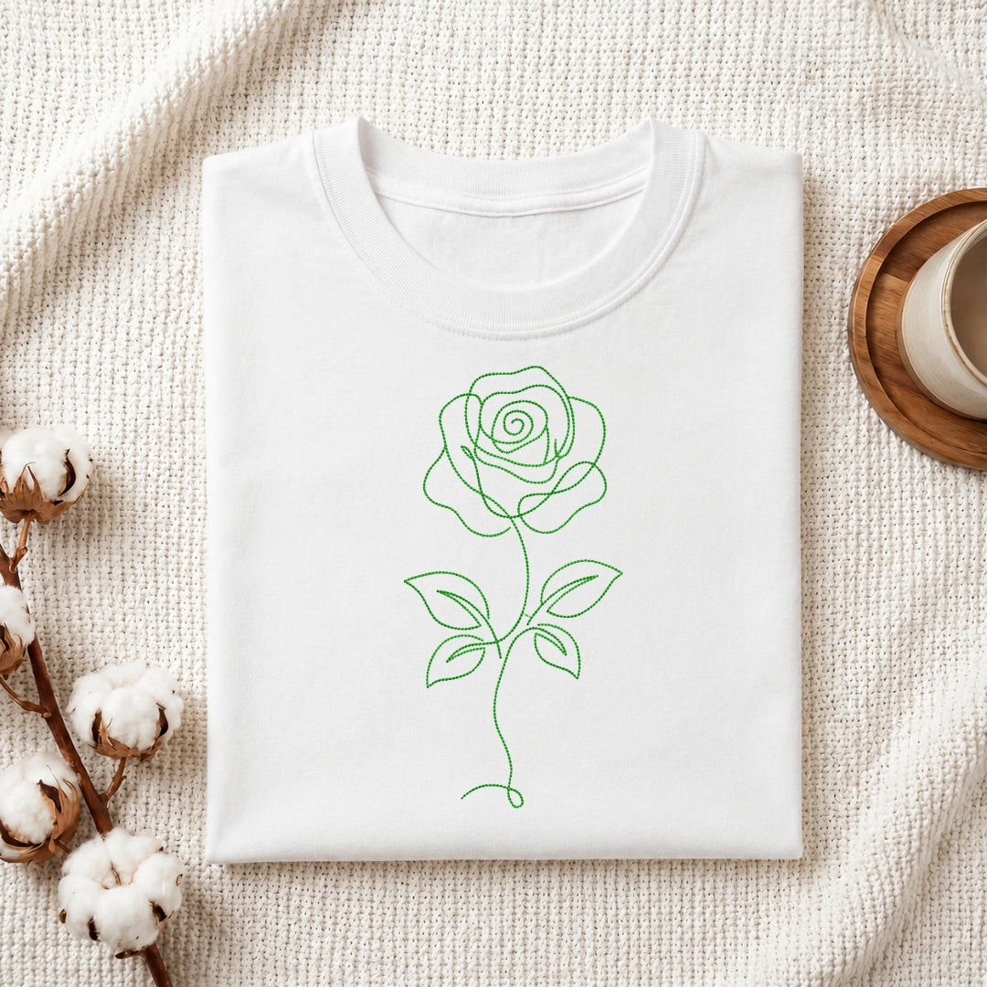 A green minimalist single line art rose embroidery design stitched on the front of a folded white cotton t-shirt.