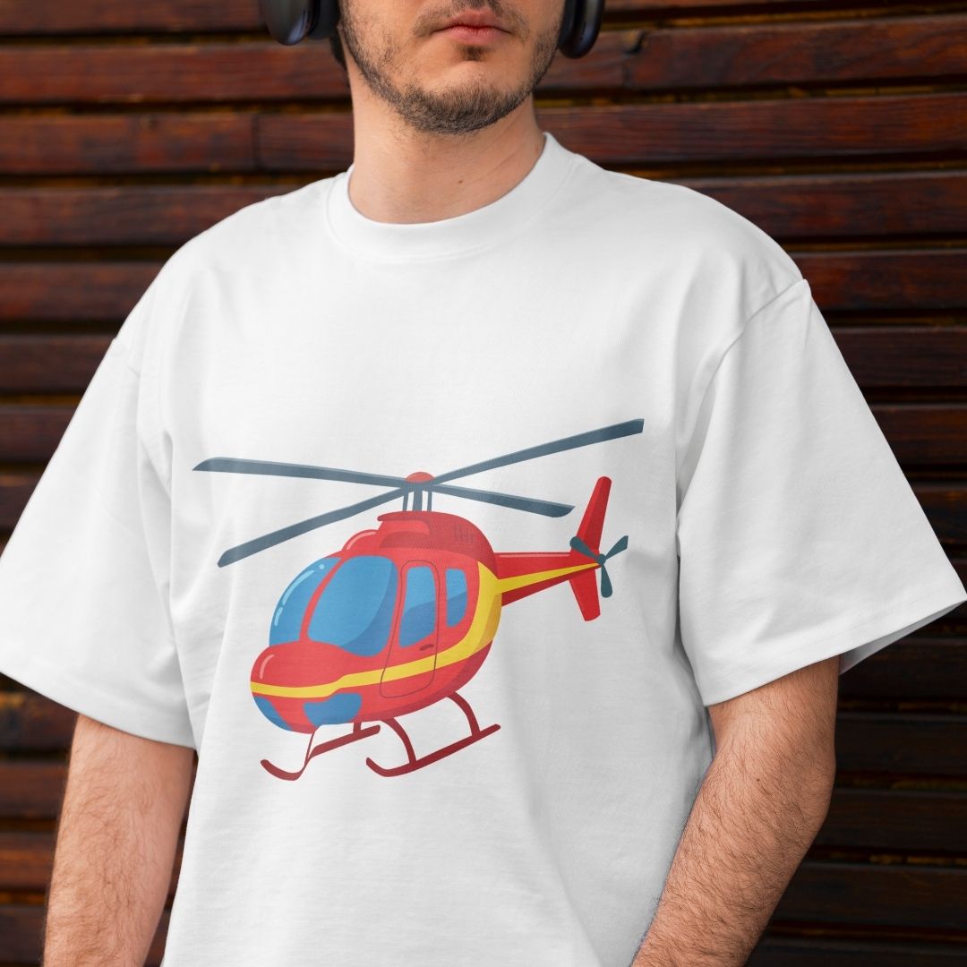 A man wearing a white crewneck t-shirt with a colorful graphic of a red, yellow, and blue helicopter on the front, set against a dark brown wooden background.