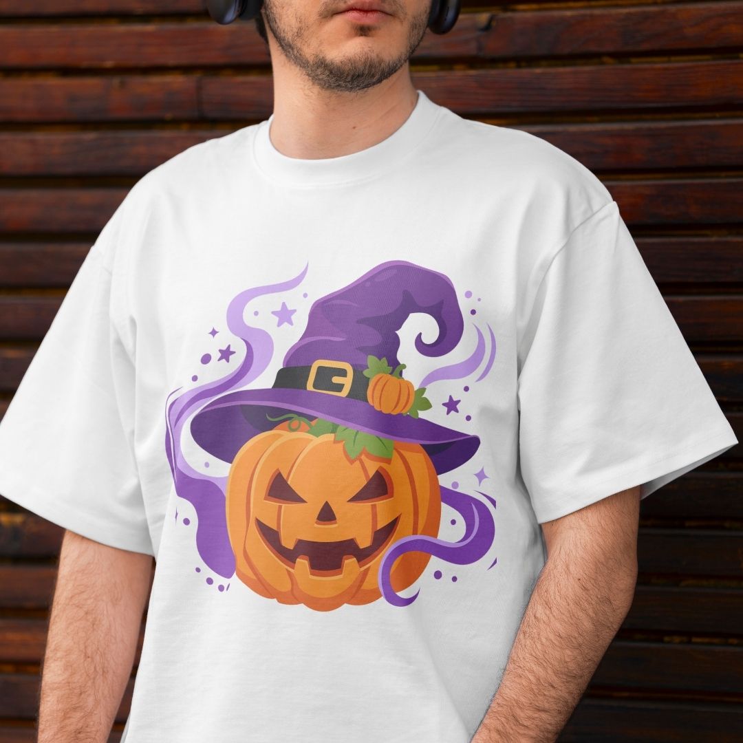 A man wearing a white t-shirt with a cartoon graphic of a jack-o'-lantern pumpkin wearing a purple witch hat, set against a dark wooden plank background.