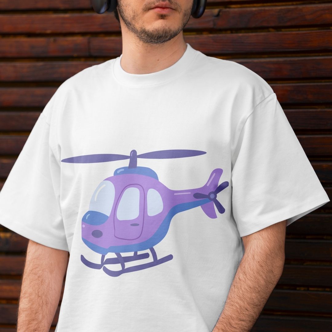 A man wearing a white crew-neck t-shirt with a purple and blue cartoon helicopter graphic on the front, set against a dark brown wooden plank background.