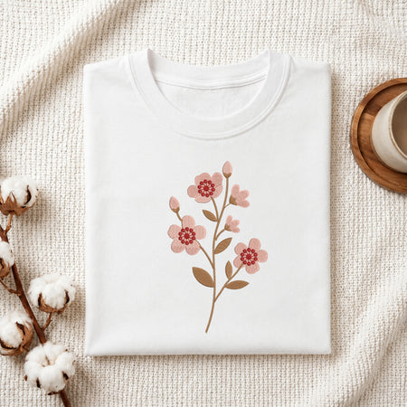 Folded white t-shirt featuring a pink blossom branch embroidery design centered on the chest.