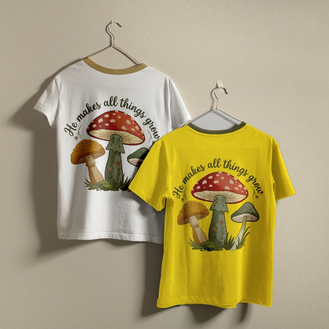 Two kids' short-sleeve t-shirts hanging on hangers against a plain beige wall. One shirt is white with a tan collar trim, and the other is bright yellow with a gray collar trim.