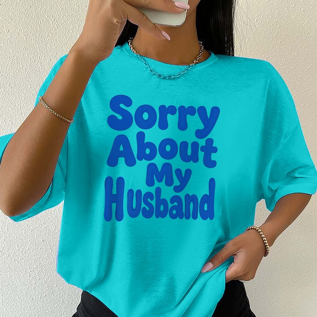 Person wearing a turquoise t-shirt with 'Sorry About My Husband' text.